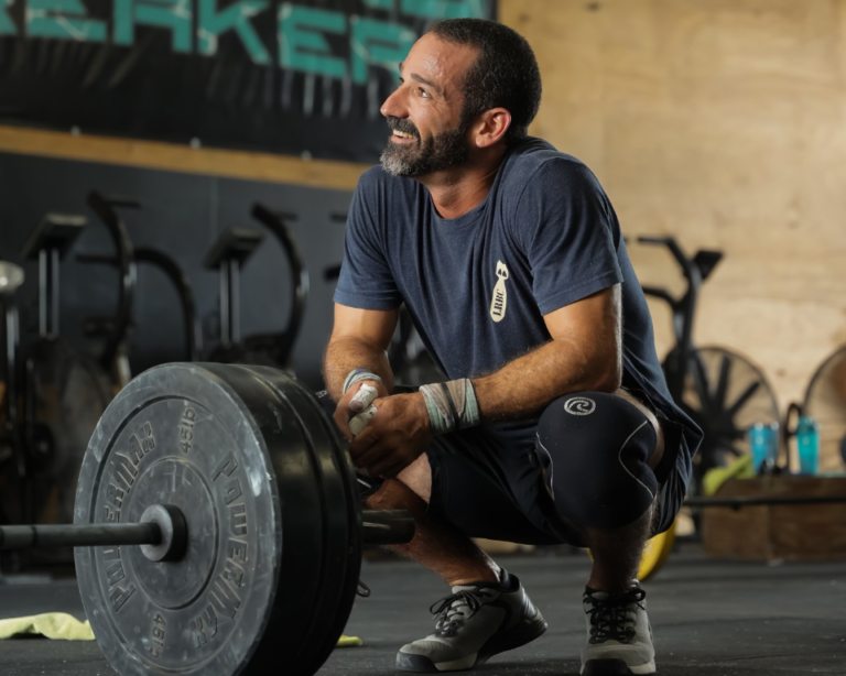 Luis Vela kneeling near a barbell